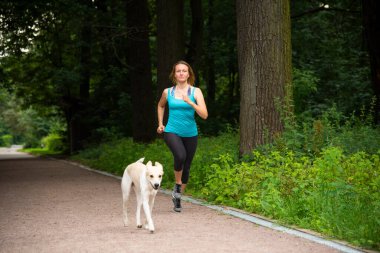 Yazın bir köpekle parkta koşuşturan güzel kız.