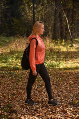 Güzel sarışın sonbaharda ormanda yürür.