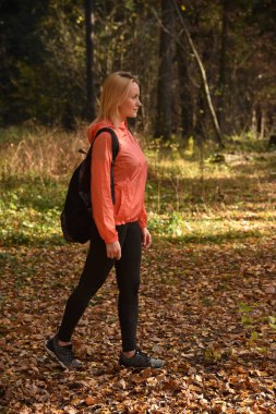 Güzel sarışın sonbaharda ormanda yürür.