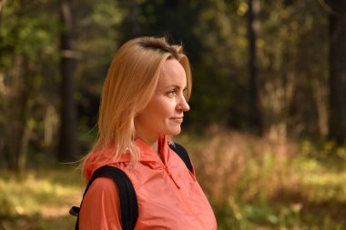 Güzel sarışın sonbaharda ormanda yürür.