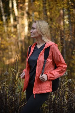 Güzel sarışın sonbaharda ormanda yürür.