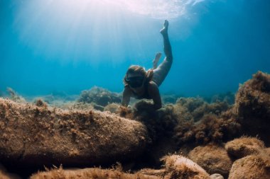Özgür kız deniz dibini deniz yosunlarıyla keşfediyor. Mavi okyanusta serbest dalış ve güzel bir ışık