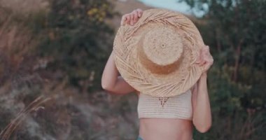 Hasır şapkalı neşeli kadın portresi. Gün batımında dışarıda mutlu bir şekilde kameraya bakıyor.