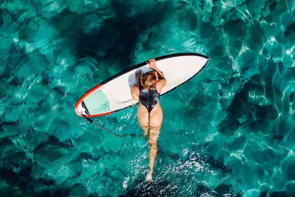 サーファーの女性はターコイズブルーの海でサーフボードで泳ぐ 空中展望 — ストック写真