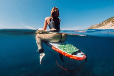 Mavi okyanusta sörf tahtasında seksi sörfçü kız, bölünmüş manzara.