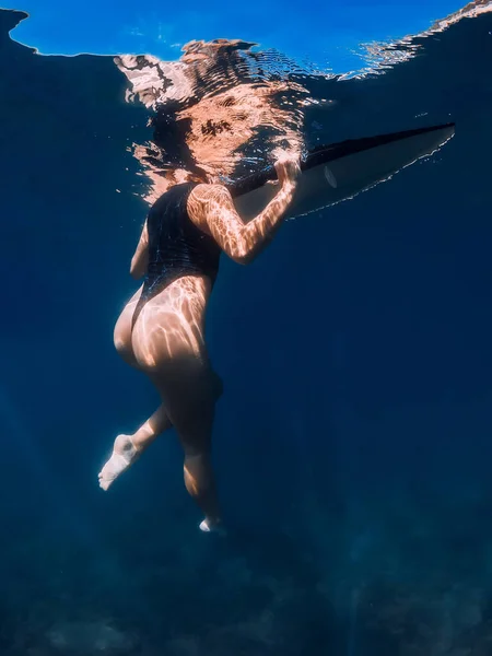 青い海でボードと一緒に泳ぐセクシーなサーファーの女の子 女性とサーフボードと水中写真 — ストック写真