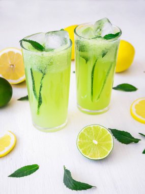 Beyaz masadaki salatalık, limon ve limonlu taze içecek.