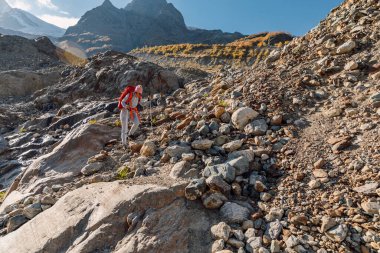 Sırt çantalı gezgin kadın dağlarda yürüyüş yapıyor. Dağda taş ve kayalarla turist