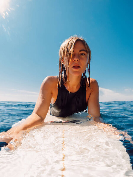 Portrait of surf girl on surfboard. Beautiful blonde woman during surfing. Surfer in ocean