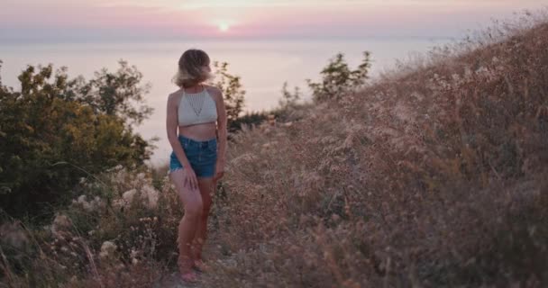 スタイリッシュな若い女の子が夕日の光でカメラにポーズをとっています 夏の日の幸せな女性の自然の美しさ — ストック動画