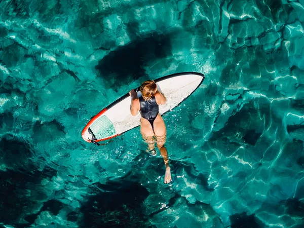 セクシーなサーファーの女性はターコイズブルーの海でサーフボードで泳いでいます 空中展望 — ストック写真