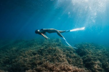 Suyun altında poz veren yüzgeçli serbest dalgıç kadın. Genç sporcu kızla serbest dalış.