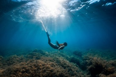 Yüzgeçli özgür bir kadın tropik okyanusta suyun altında süzülüyor..