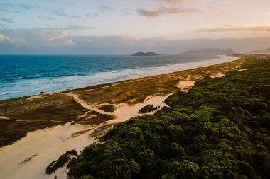 Sandy beach with dunes and ocean  with sunset lights in Campeche, Florianopolis