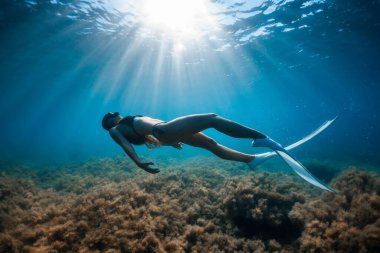 Suyun altında poz veren beyaz yüzgeçli serbest dalgıç kadın. Genç sporcu kızla serbest dalış.