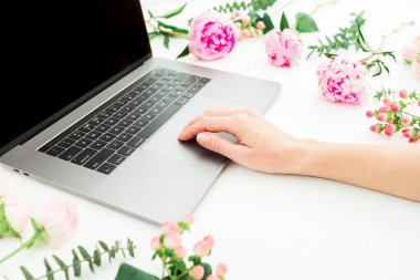 Laptop kullanan bir kadın. Çalışma odası kadın eli, dizüstü bilgisayar ve pembe çiçeklerle dolu..