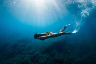 Serbest dalgıç atleti serbest dalış yüzgeçleriyle süzülür. Mavi denizdeki özgür kız.