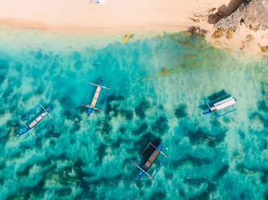 Bali, Thomas sahilinde turkuaz deniz suyu ve yerel gelenek tekneleriyle kumlu sahil manzarası.