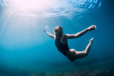 Suyun altında poz veren genç bir kadın. Serbest dalış ve güzel bayan