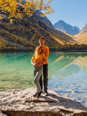 Sonbahar dağlarında Crystal Gölü 'nde poz veren mutlu çift. Dağ Gölü ve birkaç yürüyüşçü.