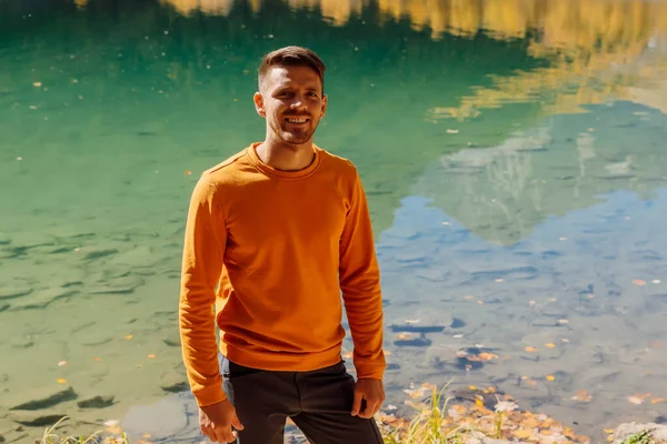 Sonbahar dağlarındaki kristal gölde mutlu bir adam. Dağ gölü ve yürüyüşçü gülümsemeli gezgin