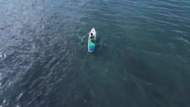 20 Nisan 2022. Sozopol, Bulgaristan. Mavi denizde ayağa kalkmış kürek çeken kadın. Denizde Red Paddle yemek masasında rahatla. Hava görünümü
