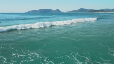 16 Nisan 2022. Brezilya, Florianopolis. Mavi okyanusta sörf tahtasında sörfçüler. Hava görünümü