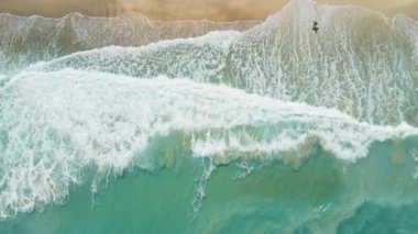 Şeffaf okyanusları, dalgaları ve sörfçüleri olan tropik bir sahil. Hava görünümü, üst görünüm