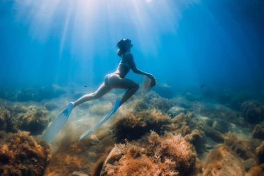 Elinde kum olan serbest dalgıç kadın. Mavi okyanusta yüzgeçleri olan serbest kız.