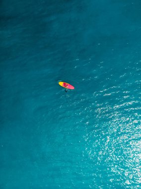 Kadınlar sakin mavi bir okyanusta ayağa kalkmış sörf tahtasında rahatlarlar. Tropikal denizde yemek bordası 