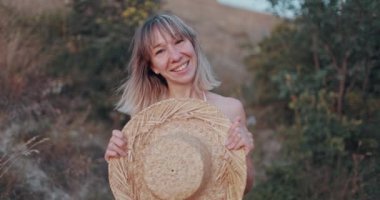 Hasır şapkalı ve mutlu bir kadının portresi açık havada başarılı bir yaşam tarzının keyfini çıkarıyor.