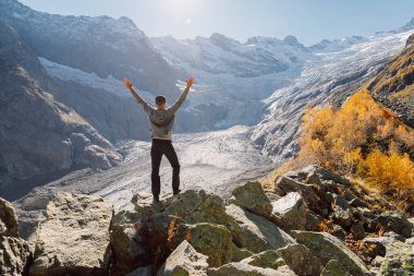 Dağlarda yürüyüş yapan adamla motivasyon konsepti. Buzul ve yürüyüşçü turistlerle dolu bir dağ.