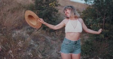 Mutlu duyguları olan neşeli bir kadın ve gün batımında açık havada dans ediyor.