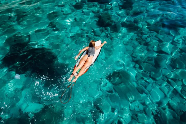 Surfer Girl Rowing Surfboard Transparent Turquoise Ocean Aerial Drone View — стоковое фото