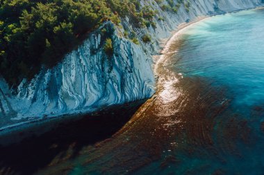 Aerial view of scenic coastline with blue sea and cliffs with pine forest. Summer day on quiet blue sea