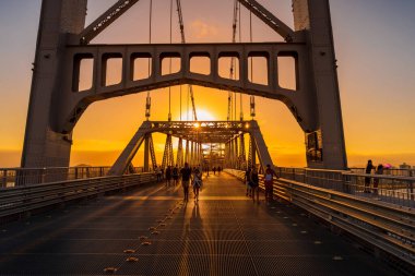 May 1, 2022. Florianopolis, Brazil. Hercilio luz cable bridge with walking people and sunset sky in Florianopolis, Brazil