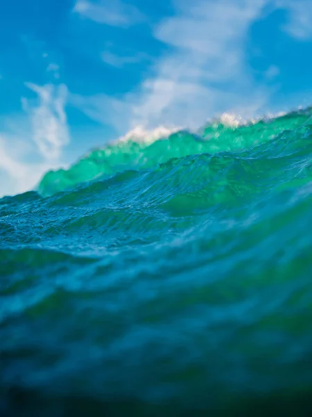 Breaking ocean wave with sun light. Liquid texture of water