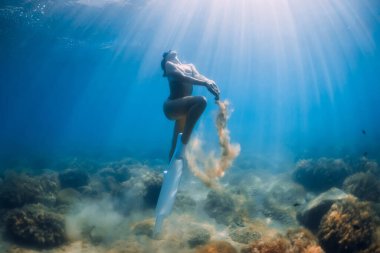 Free diver woman play with sand underwater. Lady freediver in blue sea