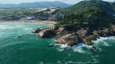Scenic landscape with Joaquina beach, rocks, mountains and Atlantic ocean with waves in Brazil. Aerial view