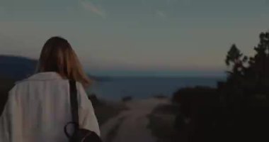 Woman walking along on the path in outdoor with sunset light. Weekend in the mountains