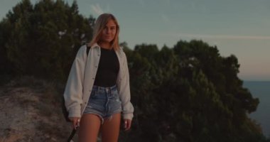 Portrait of young blonde woman in shorts posing outdoor on sunset.