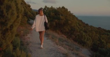 Woman walking along on the path in outdoor with sunset light. Weekend in the mountains