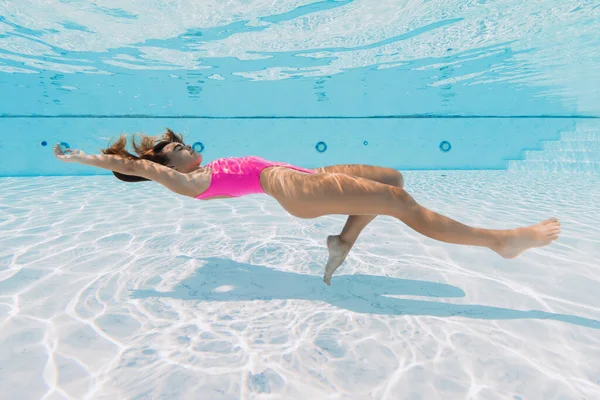 魅力的なスポーティーな女性でピンクの水着リラックスしてポーズ水中でプール — ストック写真