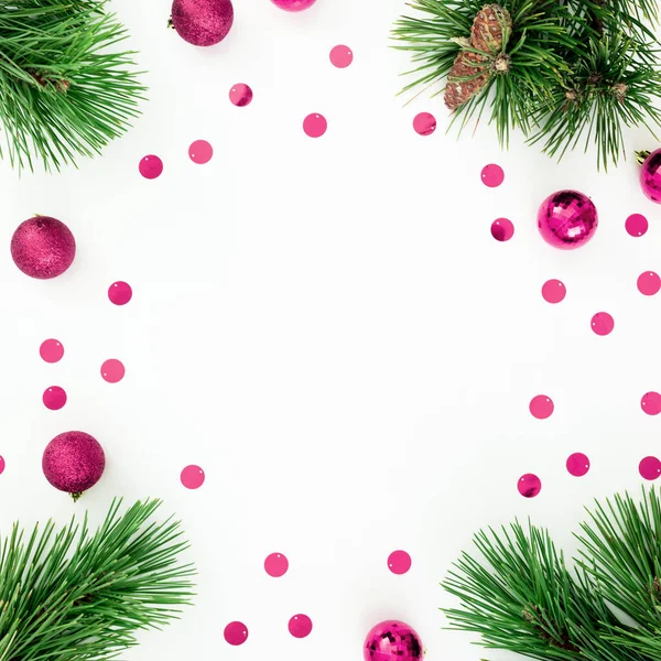 Christmas frame made of pine branches and decoration balls with confetti on white. Flat lay, top view
