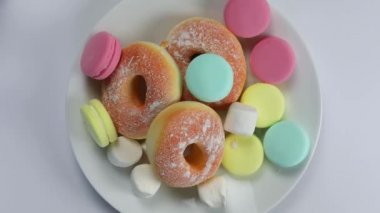 Dur işaretini gösteren eller reddeden donut, badem kurabiyesi, fast food ve şekeri beyaz tabakta gösteriyor, sağlık kilo kaybı kavramı renkli