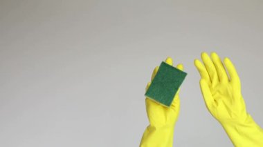 Kadın sarı koruyucu lastik eldiven ve beyaz arka planda temizlik süngeri verdi. Metin veya reklam temizleme konsepti için kopyalama alanı olan 4k video