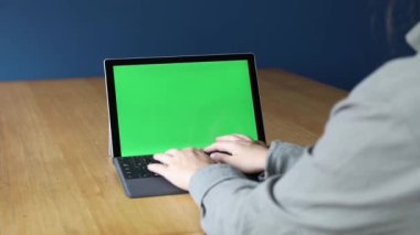 Evde bilgisayar başında çalışan bir iş adamının omzunun üstünden, masadaki dizüstü bilgisayarla yeşil ekrana bakarken. Ofisteki kişi dizüstü bilgisayarı yeşil ekranlı kullanıyor, ahşap masada oturuyor, kopyalama alanı. çalışma konsepti