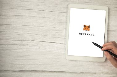 Metamask uygulaması beyaz dijital tablet üzerinde tahta masa üzerinde kopya alanı, yazılım kripto para cüzdanı sanal