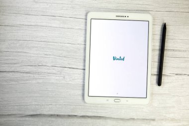 Hollanda, Aralık 2021 Vinted mobil uygulaması beyaz dijital tablet üzerinde ahşap masa üzerinde. Kullanılmış giysiler satılıyor Metin için boşluk kopyalanıyor