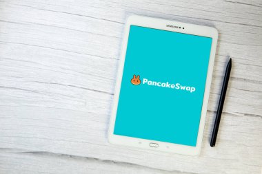 Hollanda, Aralık 2021 Pancakeswap logosu. Kripto para birimi DEX, tablet merkezsizleştirildi. Kripto jetonu, dijital para Bitcoin, Ethereum. İş, metin için ahşap masa alanına yatırım yapmak, satın almak, satmak ve satmak için engelleme platformu takas etmek.